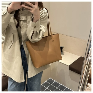 Macro view of brown leather tote bag with fine matte texture and golden logo detail