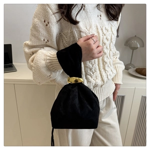 Detail of black velvet drawstring bucket bag featuring a large gold metal ring handle