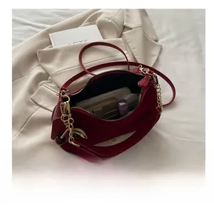 Vue détaillée du sac à bandoulière rouge foncé montrant sa capacité et un charm cerise
