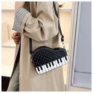 Detail of piano-shaped crossbody bag with musical key pattern on a khaki trench coat