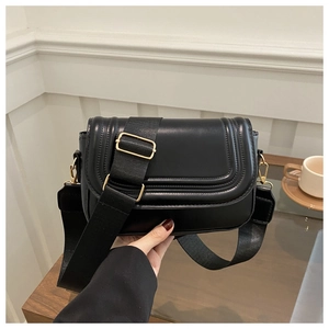 Close-up of black saddle bag featuring smooth leather texture and golden metal hardware