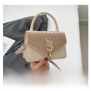 Detail of crossbody bag with woven flap, gold S-clasp, and tassel accessory