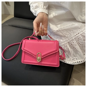 Detail of hot pink crossbody bag showing golden oval twist lock and envelope flap