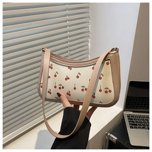 Detail of a cream underarm bag with red cherry prints and a chic chain strap
