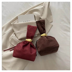 Detail of burgundy and dark brown drawstring bucket bags with golden metal handles