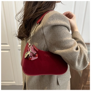 Détail du sac hobo rouge avec chaîne dorée et pendentif cerise décoratif