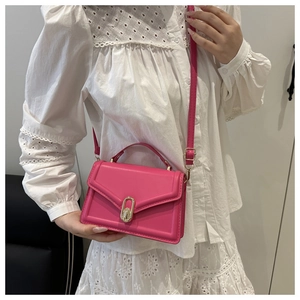 Detailed close-up of hot pink crossbody bag featuring a golden oval twist-lock fastener