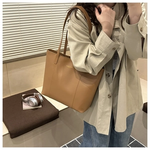 Detail of caramel leather tote bag with slim shoulder straps and gold metallic logo
