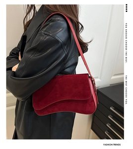 Detail view of burgundy suede shoulder bag with unique curved wave flap and hourglass base
