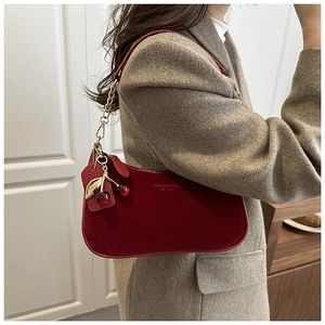 Détail du sac à bandoulière en daim rouge foncé avec pendentif cerise et chaîne dorée