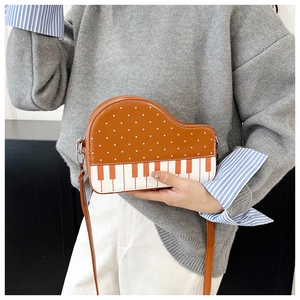 Detail of creative piano crossbody bag featuring white polka dots and keyboard pattern