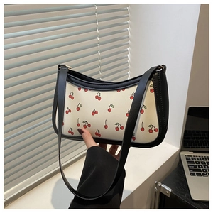 Detail shot of cream underarm bag with red cherry prints and black leather chain strap