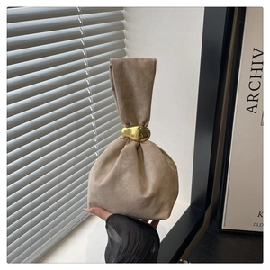 Close-up of khaki suede bucket bag featuring a unique gold metal ring closure detail