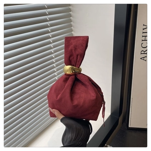 Detail of burgundy suede bucket bag with thick gold metal ring handle and drawstrings