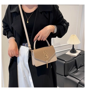 Detail of two-tone shoulder bag with snake pattern flap, metal SS logo and gold tassel
