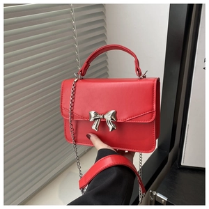 Detail of red mini square bag with silver bow ornament and textured leather