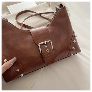 Close-up of vintage brown leather bag with silver rivets and large buckle detailing