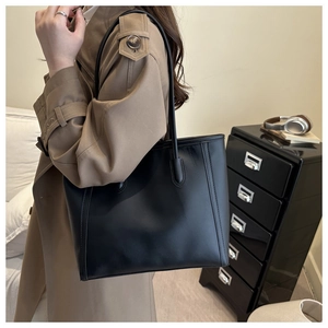 Minimalistische schwarze Totebag aus mattem Leder in Seitenansicht an einer Schulter