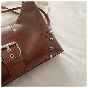 Detailed texture of brown retro PU leather bag featuring silver cone rivets and fine stitching