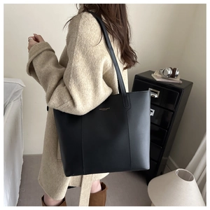 Detail of minimalist black leather tote bag with gold lettering and precise stitching