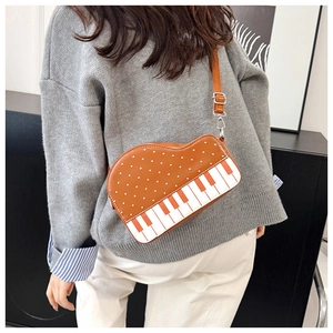 Detail of creative piano-shaped crossbody bag with orange-white keys and polka dots