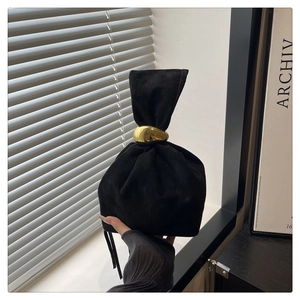 Detail of black suede drawstring bucket bag with a polished gold metal ring handle