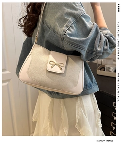 Detail of minimalist beige shoulder bag with golden bow buckle on soft suede fabric