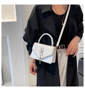 Detail of white snake-embossed handbag with gold hardware and top handle shown on model