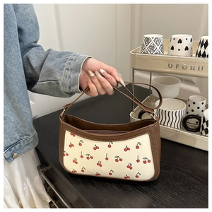Detail showing cherry print pattern and leather trim on this stylish underarm bag