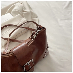 Detail of brown leather rivet bag with silver metal studs and decorative belt buckle