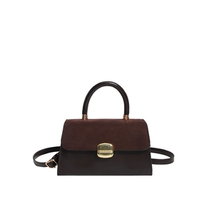 Brown leather handbag with suede flap and gold metal buckle in minimalist trapezoid shape