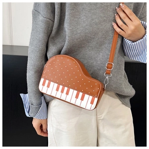 Detail view of piano-shaped crossbody bag featuring polka dots and musical keyboard design