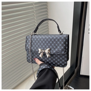 Detail of blue geometric patterns and silver metal bow on a black crossbody bag