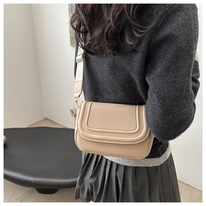 Detail view of beige crossbody saddle bag with U-shaped stitching and wide strap