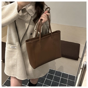 Dunkelbraune Leder-Shopper-Tasche kombiniert mit einem beigen Wollmantel im Alltag