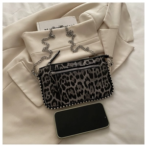 Detail van luipaardprint crossbodytas met zilveren klinknagels en metalen ketting