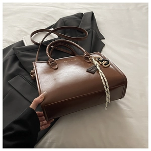 Détail du sac cabas marron foncé avec pendentif chocolat sur la poignée tissée