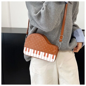 Detail view of piano-shaped crossbody bag with white polka dots and adjustable strap