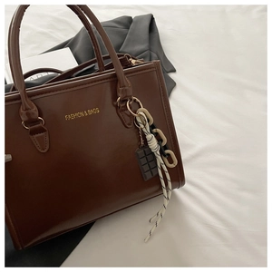Sac cabas en cuir marron foncé avec poignées cylindriques et détail de breloque