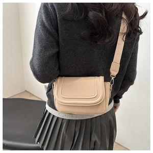 Detail of apricot faux leather saddle bag with U-shaped stitching and wide shoulder strap