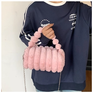 Détail du sac à main en fausse fourrure rose avec rayures et poignée à pompons doux