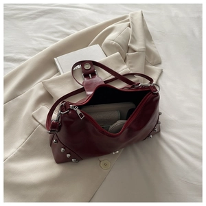 Detail shot of a burgundy rivets shoulder bag showing large capacity and shiny finish