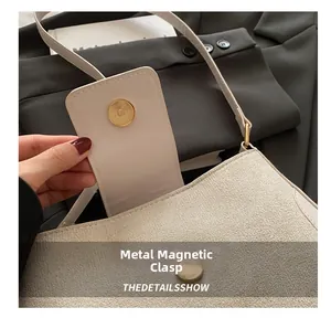 Detail of the magnetic metal clasp on an oatmeal leather shoulder bag with mixed textures