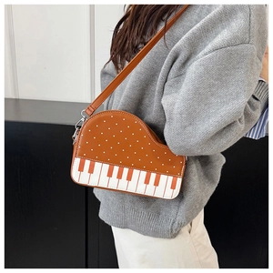 Detail of creative piano-shaped crossbody bag in brown PU leather with polka dots and strap
