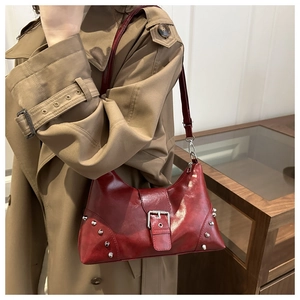 Detailed close-up of dark red vintage dumpling bag with silver rivets and metal buckle