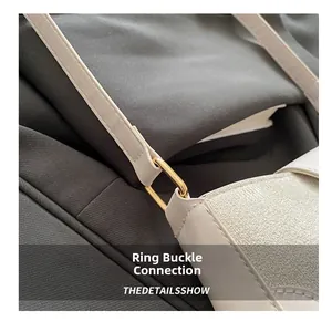 Detail of elegant gold D-ring buckle connecting strap to minimalist beige leather shoulder bag