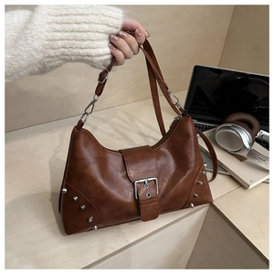 Close-up of vintage brown leather bag with silver rivets in a stylish office setting