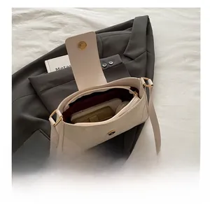 Macro view of beige shoulder bag with golden magnetic buckle and dark red lining
