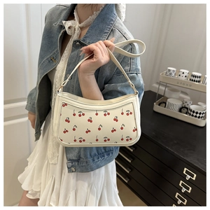 Close-up of cream underarm bag with red cherry print and premium chain detail