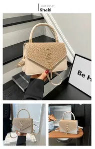 Detail of khaki crossbody bag featuring woven texture and gold S-buckle with metal fringe